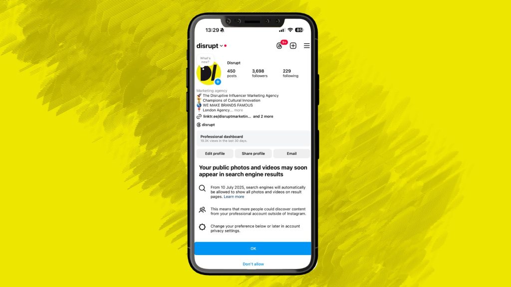 A smartphone displaying the Disrupt Marketing Instagram profile with an in-app notification stating that public photos and videos may soon appear in search engine results from July 10th 2025. The background is bright yellow with textured brushstroke design.