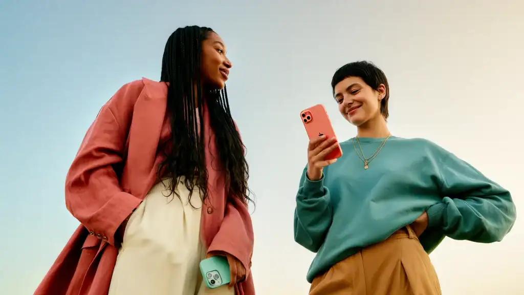 Two people standing outdoors looking at their smartphones, representing how users discover and engage with content on TikTok through search and recommendations.